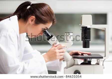 Focused female science student looking in a microscope in a laboratory