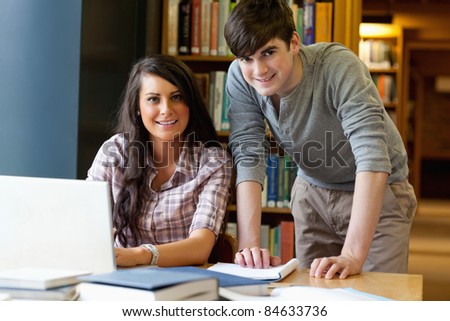 Young students working together with a laptop in the library