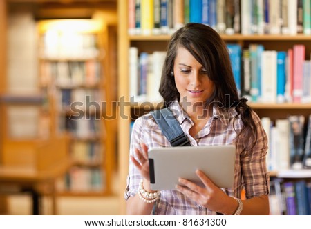 Cute young student using a tablet computer in a library