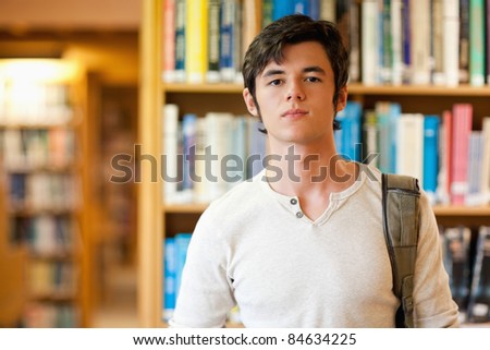 Good looking student standing up in a library