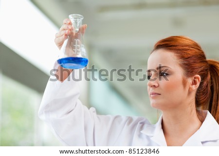 Scientist looking at a blue liquid in an Erlenmeyer flask
