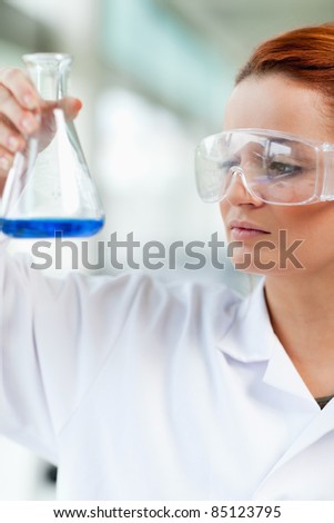 Portait of a science student looking at an Erlenmeyr flask in a laboratory