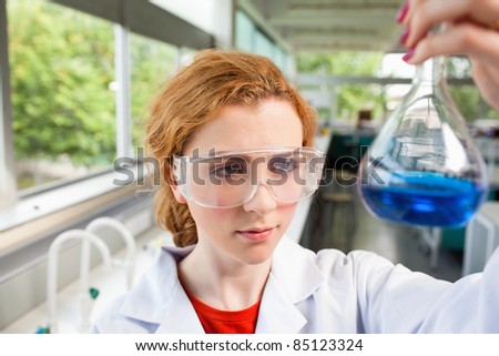 Science student looking at a flask with proctective glasses