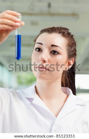 Portrait of a cute student looking at a test tube with the camera focus on the model