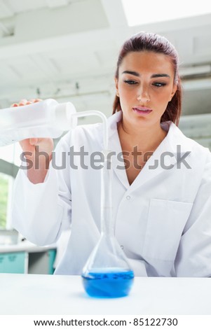 Portrait of a female scientist pouring liquid in a laboratory
