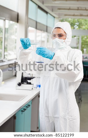 Portrait of a protected female scientist pouring liquid in a Erlenmeyer flask in a laboratory
