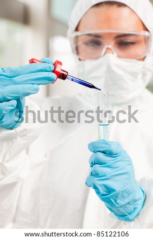 Portrait of a protected scientist dropping a liquid in a test tube in a laboratory