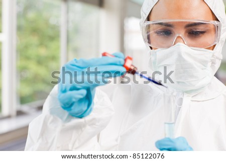Protected science student dropping a liquid in a test tube in a laboratory