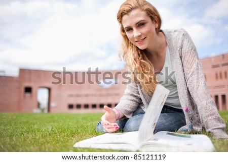 Woman posing with a book while sitting on the lawn