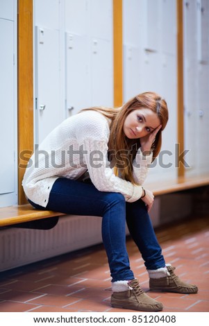 Portrait of a sad student sitting on a bench looking at the camera