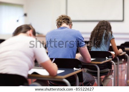 Studious young adults writing in a classroom