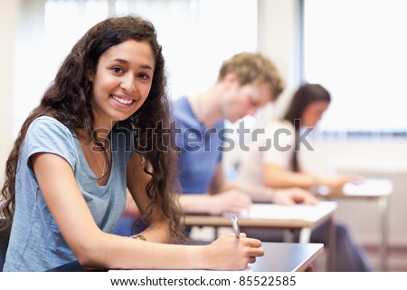 Happy young adults writing in a classroom