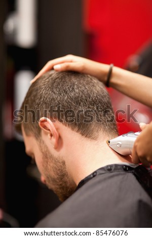 Portrait of a male young student having a haircut with a hair clippers