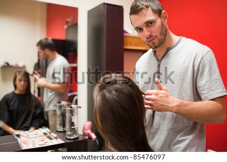 Serious male hairdresser cutting hair while looking at the camera