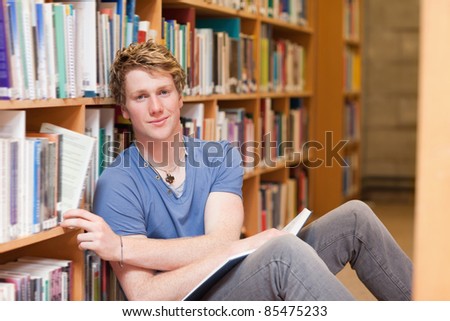 Handsome student picking a book in a library