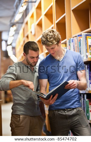 Portrait of male students looking at a book in a library