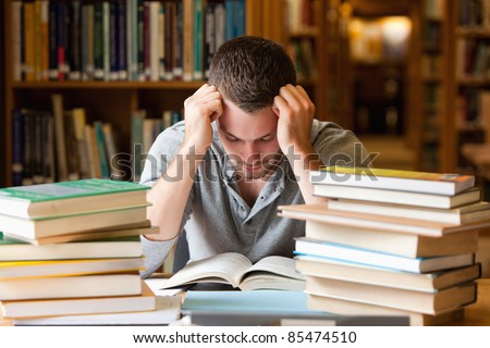 Tired student having a lot to read in a library