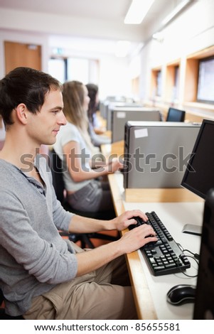 Portrait of a serious male student working with a computer in an IT room