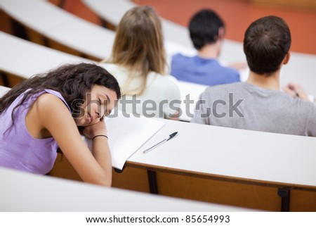 Young student sleeping during a lecture in an amphitheater