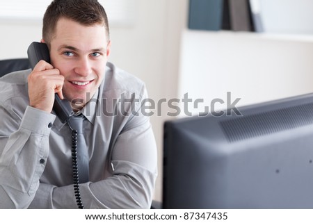 Smiling young businessman listening to the thelephone