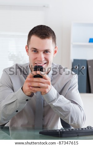 Smiling businessman getting a pleasant text message on his cellphone