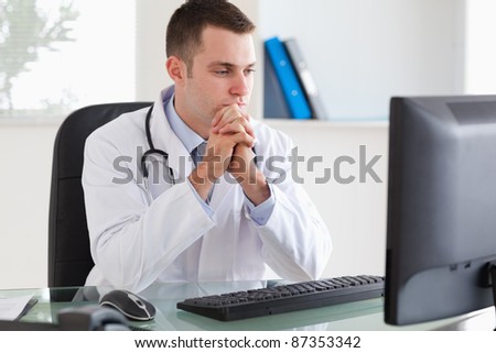 Thinking young doctor looking at his screen