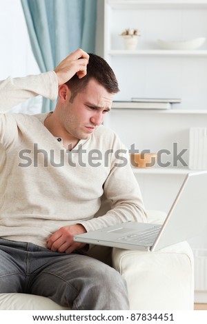 Portrait of a confused man using a notebook in living room