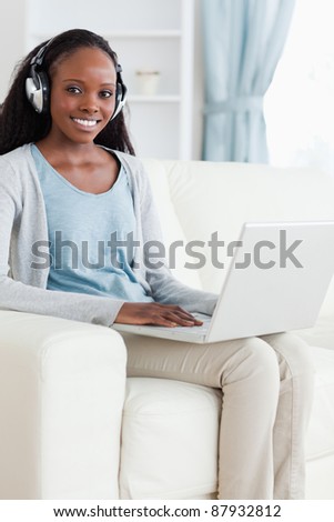 Smiling woman with headphones on using laptop