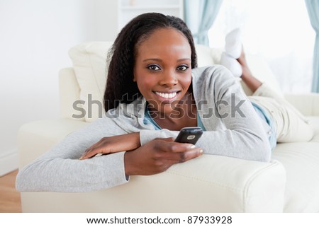 Smiling woman relaxing on sofa while texting
