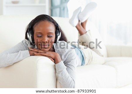 Young woman with eyes closed enjoying music on her couch