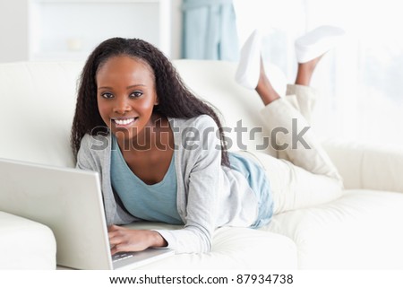 Smiling woman on her sofa surfing the internet