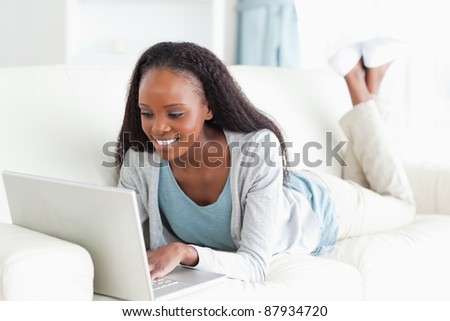 Smiling woman on her couch surfing the internet
