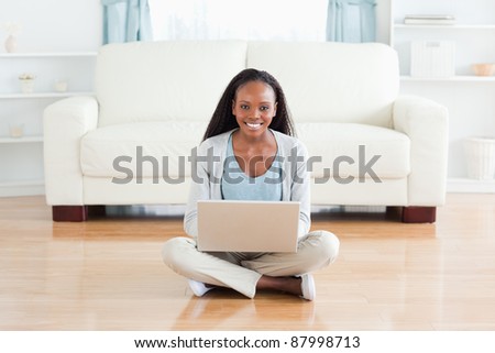 Smiling woman sitting on floor with laptop