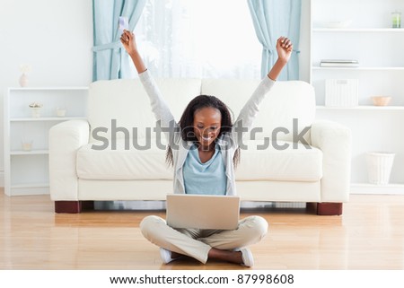 Smiling woman stretching while sitting on the floor working on notebook