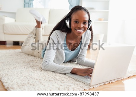 Smiling woman lying on floor with notebook enjoying music