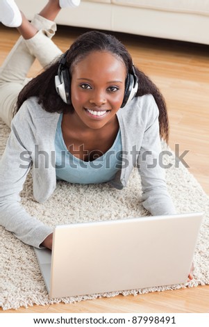 Close up of smiling woman lying on the floor with notebook listening to music