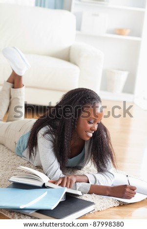 Smiling woman lying on the floor taking notes