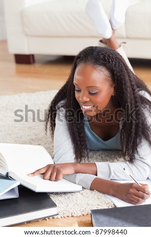 Smiling woman lying on the floor working on a book review