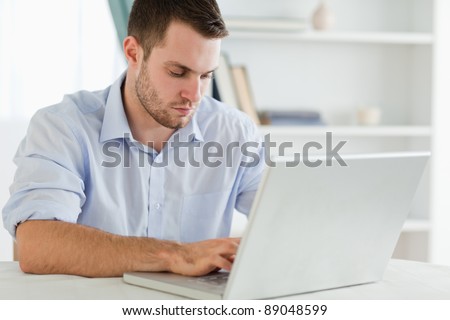 Young businessman with rolled up sleeves in his home office on his laptop