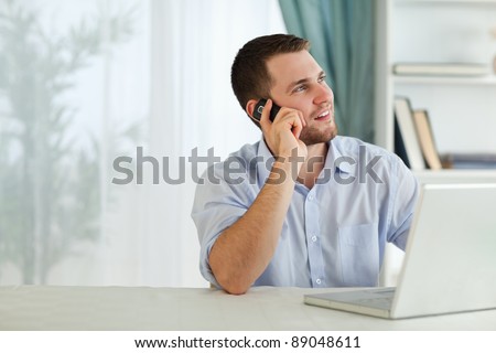 Young businessman with his cellphone in his home office