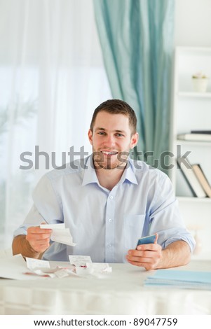 Young businessman with hand calculator checking invoices