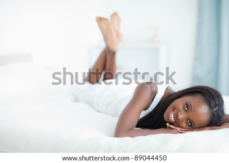 Happy woman lying on her belly in her bedroom