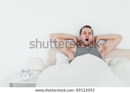 Man yawning while waking up in his bedroom