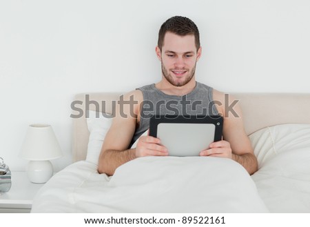 Handsome man using a tablet computer in his bedroom
