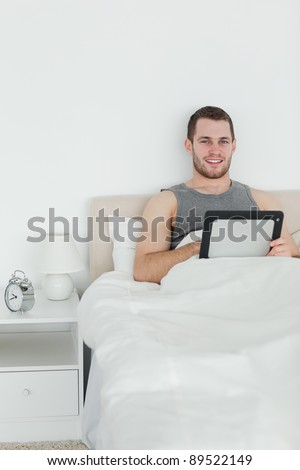 Portrait of a handsome man using a tablet computer in his bedroom