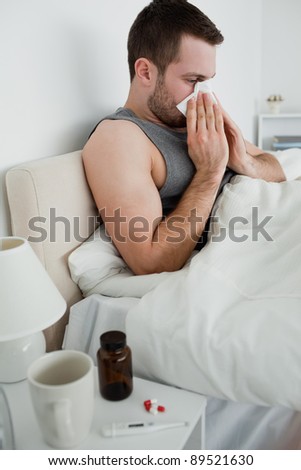 Portrait of a sick man blowing his nose in his bedroom