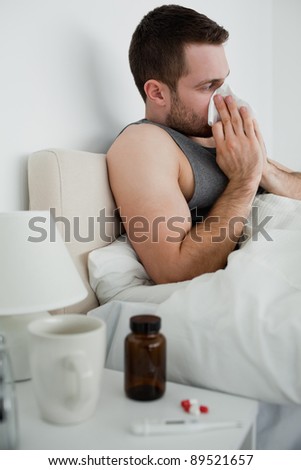 Portrait of a handsome man blowing his nose in his bedroom