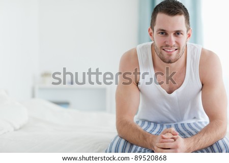 Happy man sitting on his bed while looking at the camera
