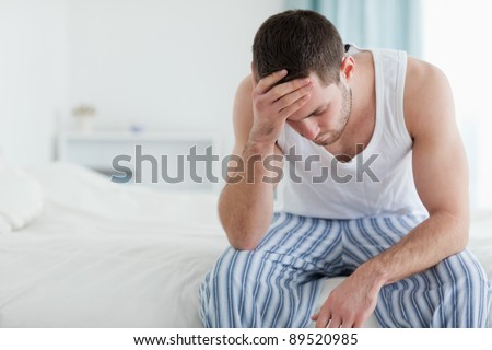 Ill Man Sitting On His Bed With His Head On His Hand