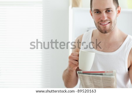 Good looking man drinking tea while reading the news in his kitchen